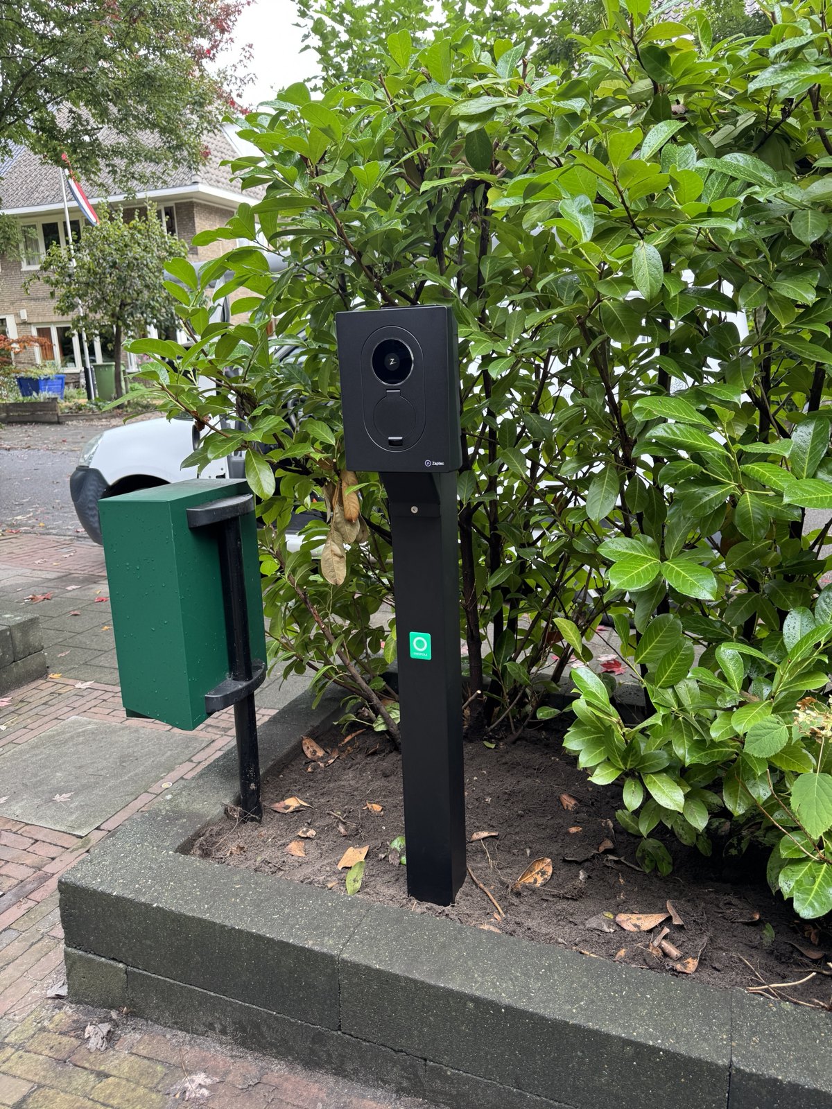 Zaptec-laadpaal op paal in een voortuin, met de stoep en straat erachter